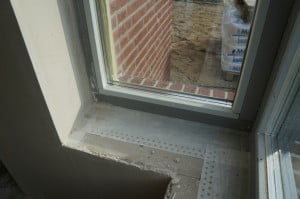 Een met Fentrim 20 luchtdicht afgeplakt kozijn tegen een massief binnenblad, afgestuukt. In dit geval een Ytong paneel, maar dat kan ook beton of kalkzandsteen zijn.